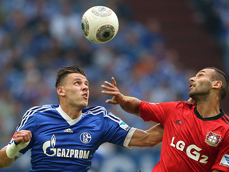 Schalkes Szalai und Leverkusens Toprak behalten den Ball im Blick.