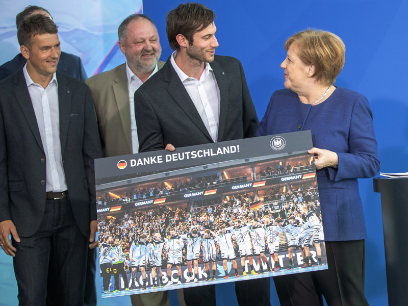 DHB-Kapit&#228;n Uwe Gensheimer &#252;bergibt Angela Merkel ein unterschriebenes Teamfoto.