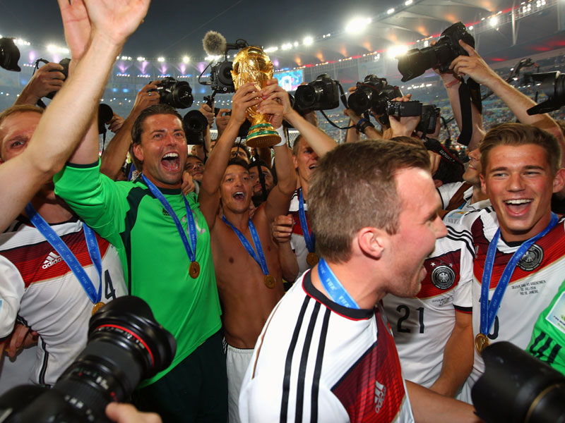 Umringt von Journalisten pr&#228;stentiert Mesut &#214;zil (Mitte) den vielen deutschen Fans den goldenen Pokal.