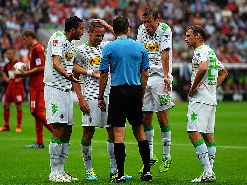 Diskussionsbedarf: Gladbachs Spieler äußern bei Schiedsrichter Dr. Felix Brych ihre Zweifel über den Elfmeterpfiff.