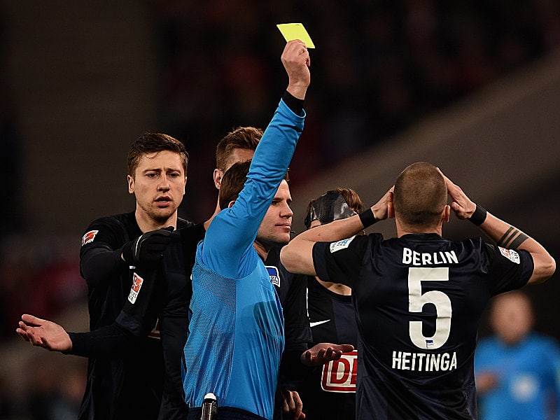 Dr. Felix Brych zeigt John Heitinga die Gelbe Karte.