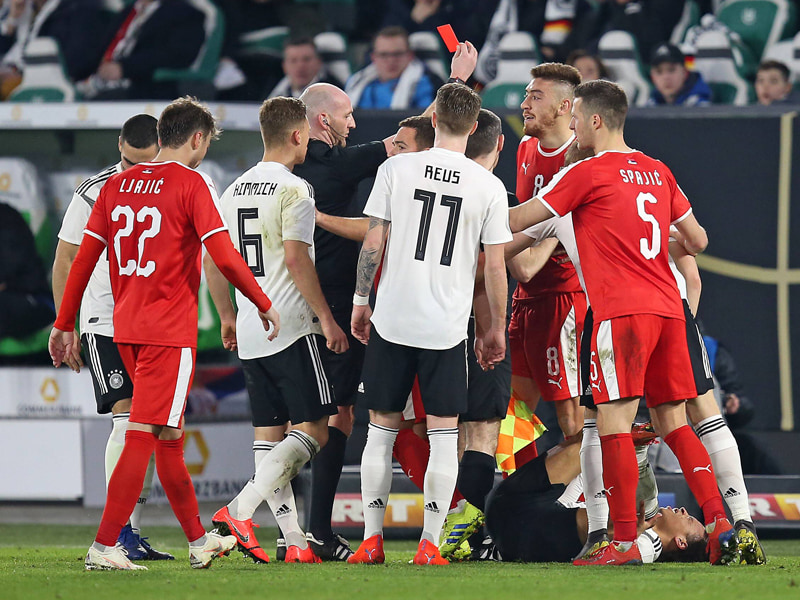 Leroy Sané krümmt sich mit Schmerzen auf dem Rasen - und Referee Bobby Madden zückt die Rote Karte.