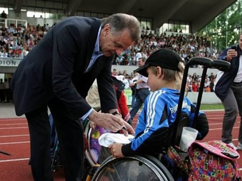Ottmar Hitzfeld gibt einem Fan im Rollstuhl ein Autogramm