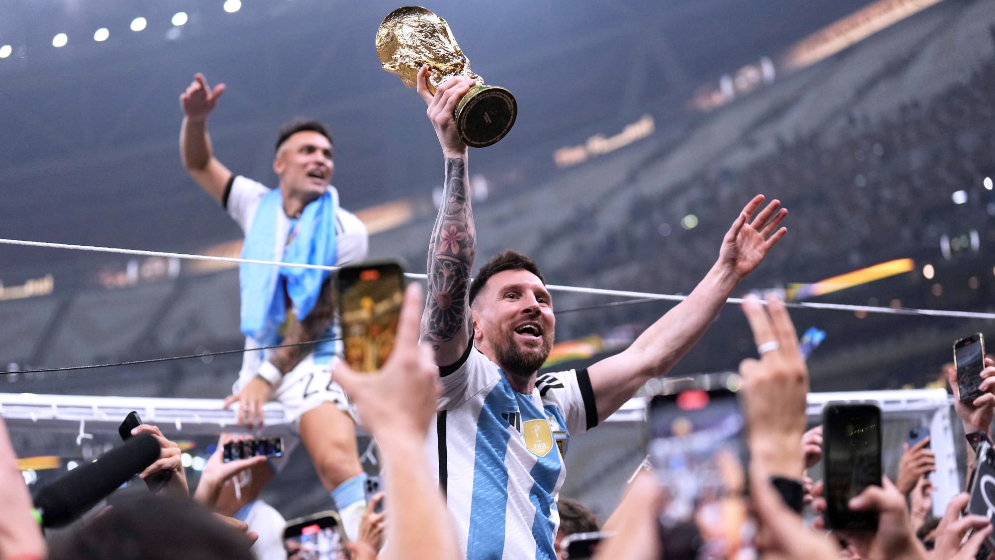 Lionel Messi streckt den WM-Pokal 2022 voller Freude in die Luft.