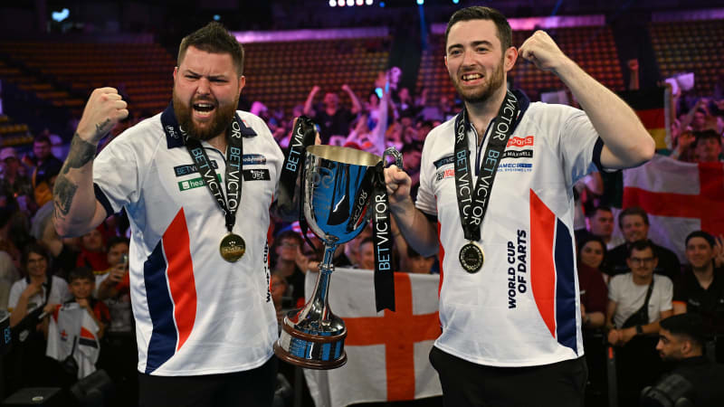 Darts: Team-WM, Finale, Eissporthalle, Michael Smith (l) und Luke Humphries aus England halten nach ihrem Sieg im Finale des World Cup of Darts gegen Österreich den Pokal.