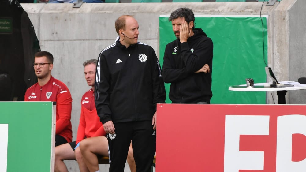 Wolfsburgs Trainer Mark van Bommel (re.) in Münster mit dem Vierten Offiziellen Tobias Fritsch.