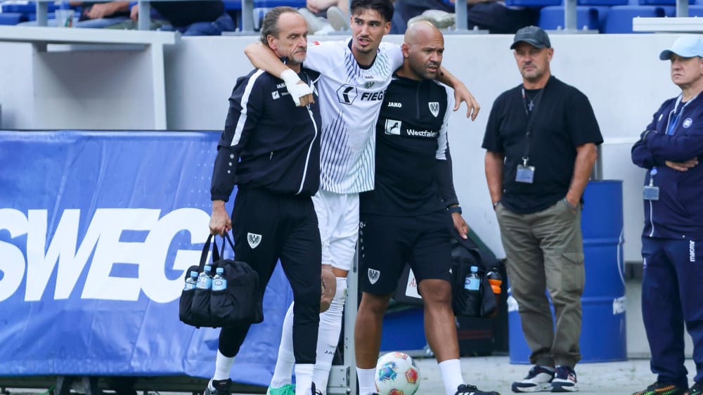 Münsters Antonio Tikvic wird mit dick bandagiertem Knie vom Platz geführt.