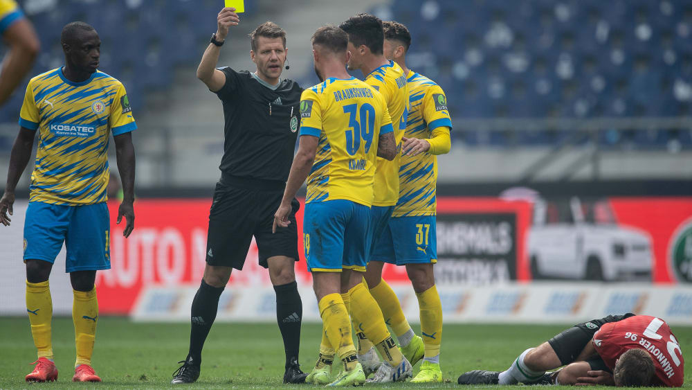 Es ging intensiv zur Sache: Referee Patrick Ittrich zückt die Gelbe Karte.
