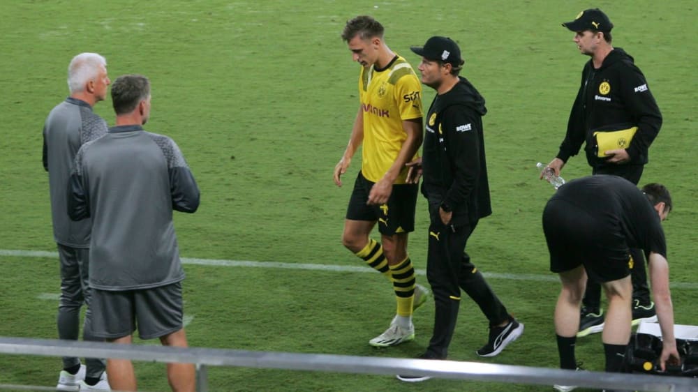 Nico Schlotterbeck wird angeschlagen von Coach Edin Terzic vom Feld begleitet.