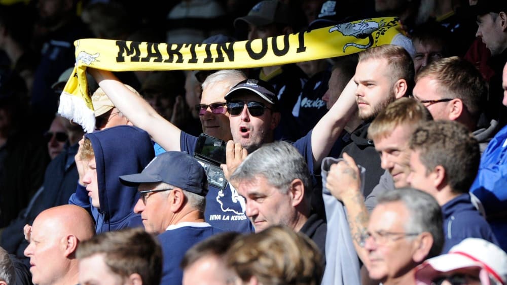 Ein Fan von Southend United hält einen Schal mit Botschaft gegen den Besitzer hoch.