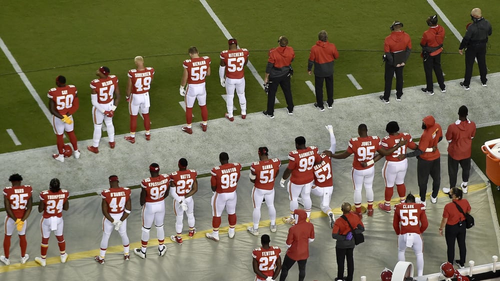 Spieler der Kansas City Chiefs lauschen der US-Hymne, einige haken ein - und Alex Okafor kniet mit erhobener Faust.