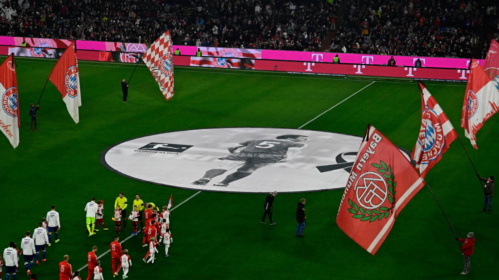 Bayern Munich and Hoffenheim's players arrive on the pitch as Bayern Munich's staff members stand with flags around a picture of late German football legend Franz Beckenbauer ahead of the German first division Bundesliga football match between FC Bayern Munich and TSG 1899 Hoffenheim in Munich, southern Germany, on January 12, 2024. (Photo by Tobias SCHWARZ / AFP) / DFL REGULATIONS PROHIBIT ANY USE OF PHOTOGRAPHS AS IMAGE SEQUENCES AND/OR QUASI-VIDEO (Photo by TOBIAS SCHWARZ/AFP via Getty Images)