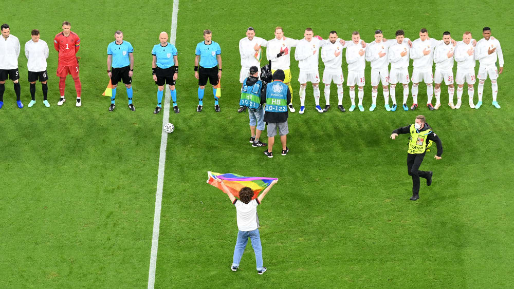 Ein Mann pr&#228;sentiert w&#228;hrend der ungarischen Nationalhymne eine Regenbogen-Fahne.