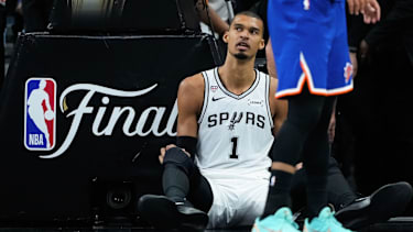 San Antonio Spurs forward Victor Wembanyama sits on the floor after a foul during the second half of Game 5 of the NBA Finals basketball series against the New York Knicks, Saturday, June 13, 2026, in San Antonio. (AP Photo/Ross D. Franklin)