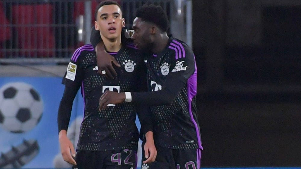 Die Bayern-Spieler Jamal Musiala (li.) und Alphonso Davies bejubeln Arm im Arm ein Tor.