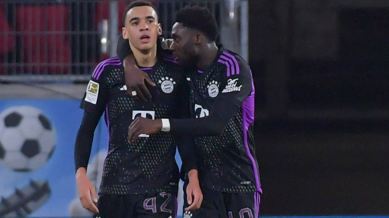 Die Bayern-Spieler Jamal Musiala (li.) und Alphonso Davies bejubeln Arm im Arm ein Tor.