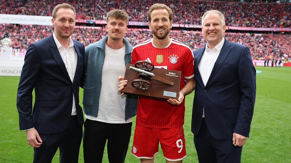Aller guten Dinge sind drei: Die kicker-Reporter Georg Holzner, Mario Krischel und Frank Linkesch &uuml;berreichen Harry Kane die kicker-Torj&auml;gerkanone.