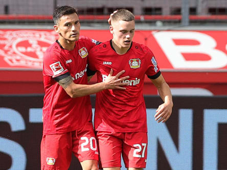 Charles Aranguiz nimmt Mitspieler Florian Wirtz in den Arm.