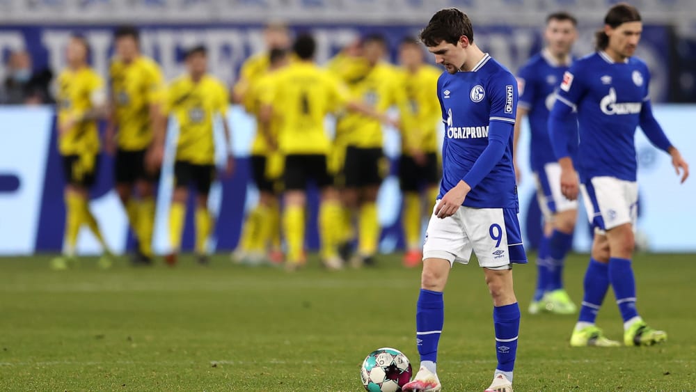 Im Hintergrund jubeln die Dortmunder, vorne senken die Schalker die Köpfe.