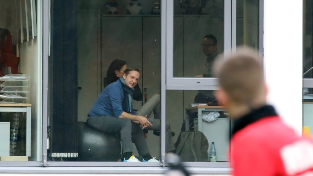 Horst Heldt sitzt im Büro und verfolgt das Training