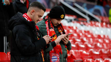 Bayern-Schal, ManUnited-Mütze und Handy in der Hand: Klubs haben noch Potenzial beim E-Commerce.