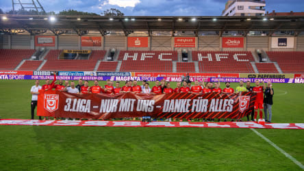 Die Spieler und Verantwortlichen des Halleschen FC freuen sich mit einem Banner über den Klassenerhalt.