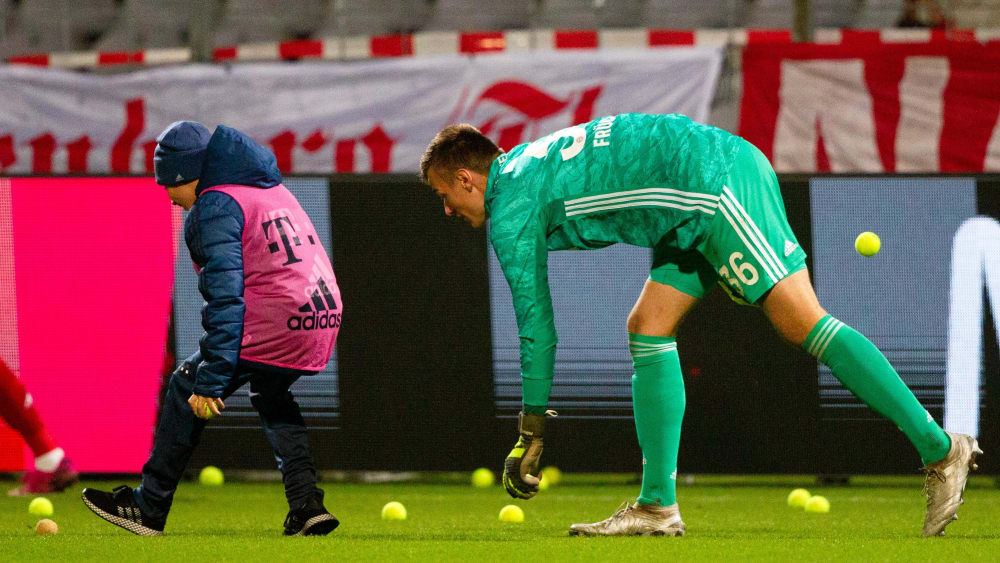 Bayern-II-Keeper Christian Früchtl hilft beim Aufräumen der von Bayern-Fans auf das Spielfeld geworfenen Tennisbälle.
