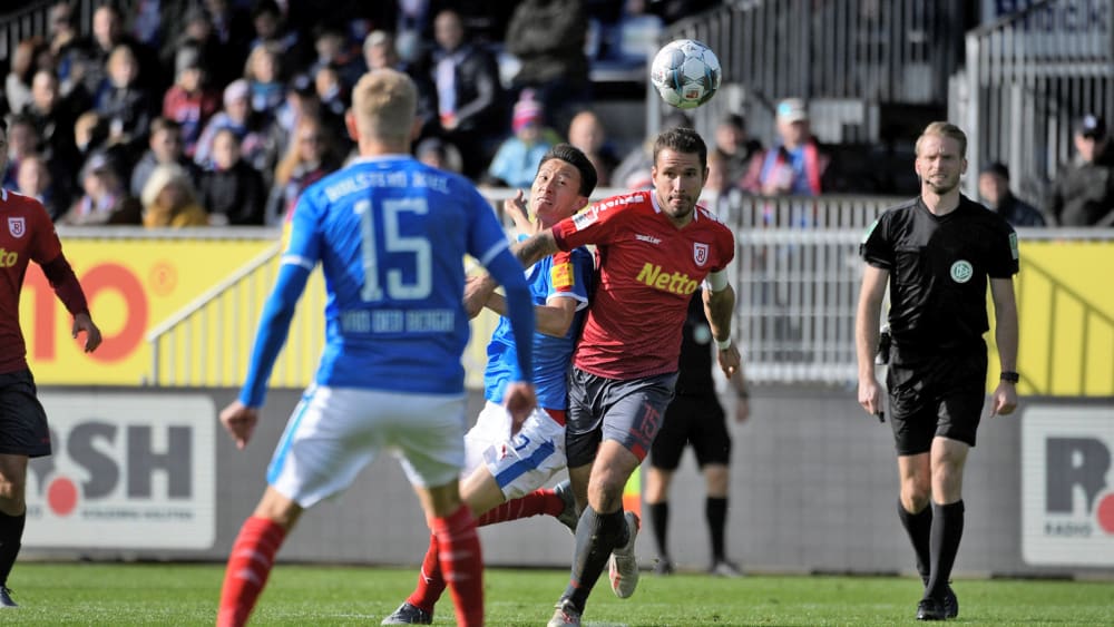 Marco Grüttner (re., Jahn Regensburg) und Jae-Sung Lee (Kiel) im Zweikampf