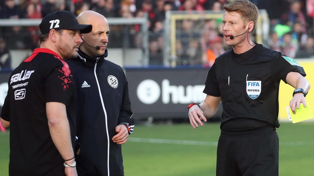 Schiedsrichter Christian Dingert (rechts) zeigt Paderborns Trainer Steffen Baumgart die Gelbe Karte.